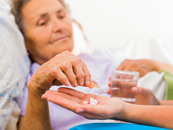 A lburred picture of an elderly woman being handed her medication