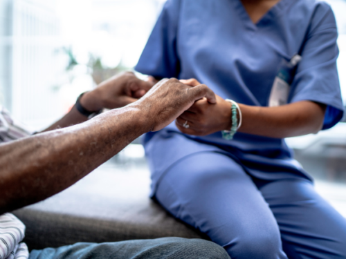 A close up of a nurse holding the hands of a patient