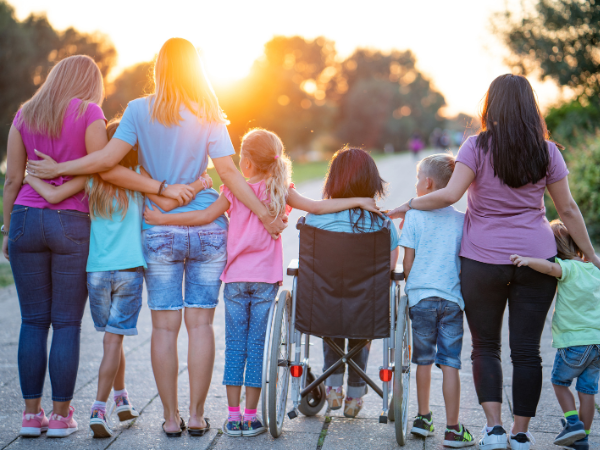 A family group looking away from the camera with their arms all linked. In the centre sits a woman in a wheelchair.
